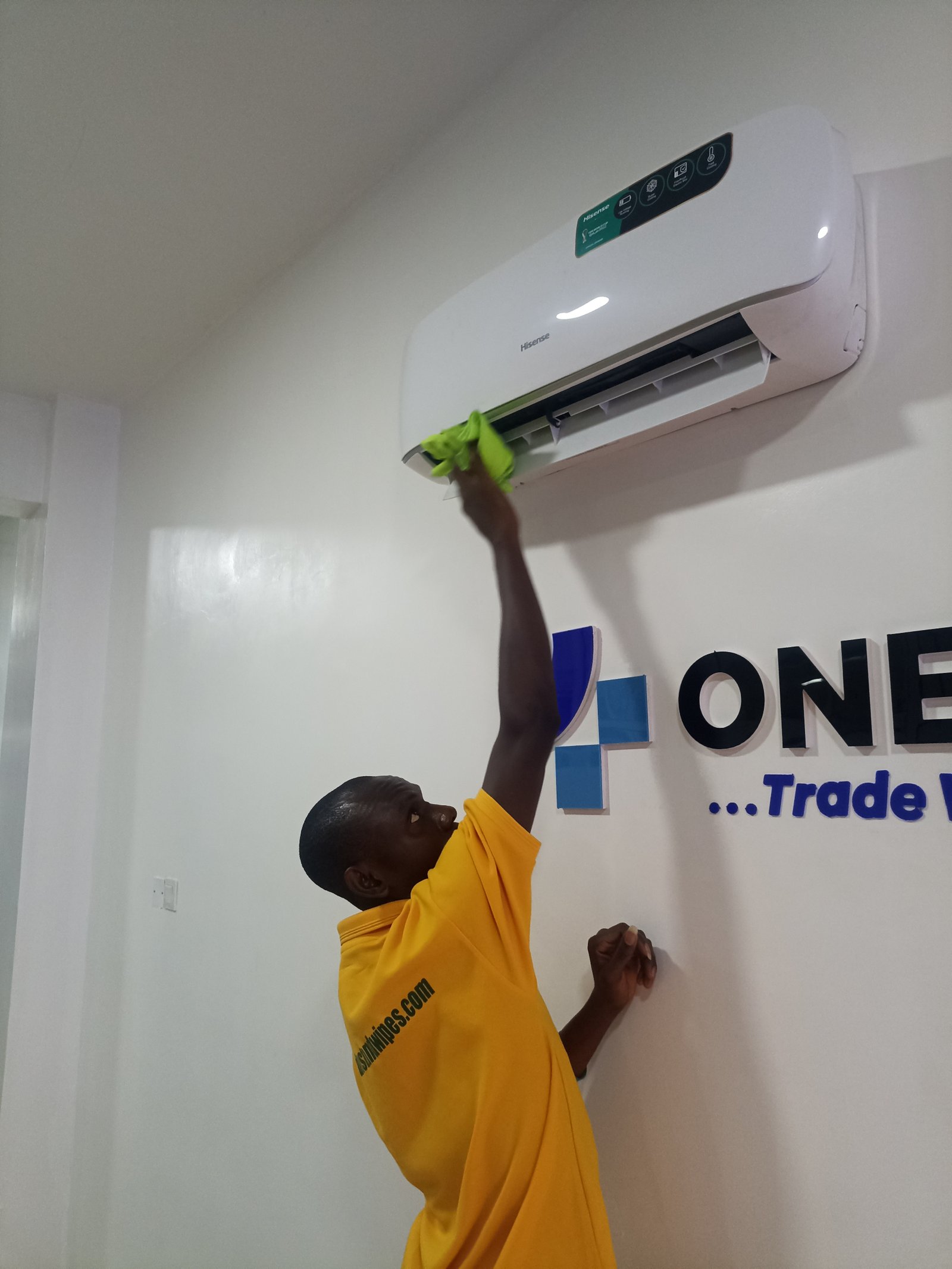 Dust and Wipes staff in yellow cleaning Hisense AC unit at client office