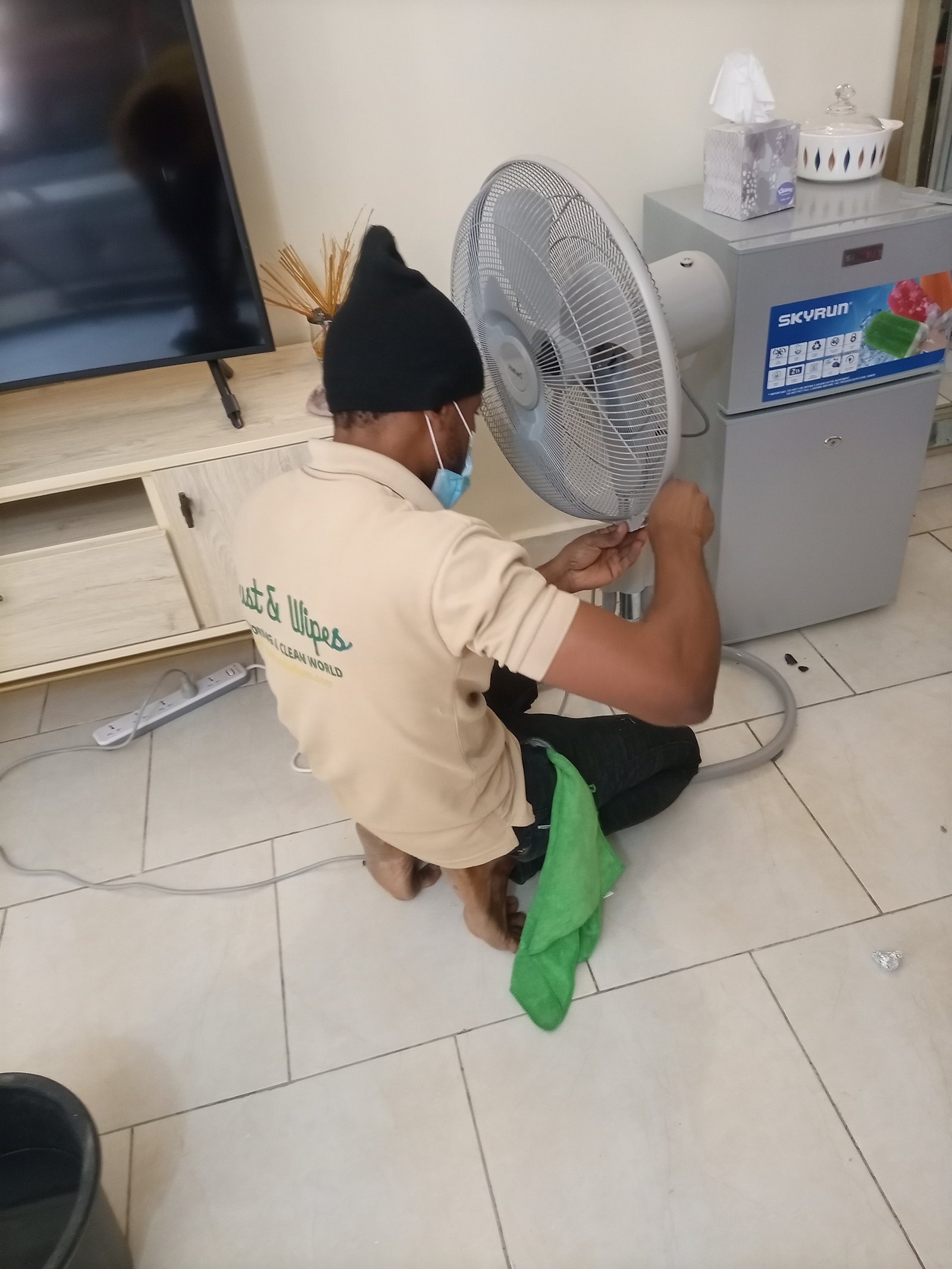 Dust and Wipes staff in cream uniform cleaning residential fan