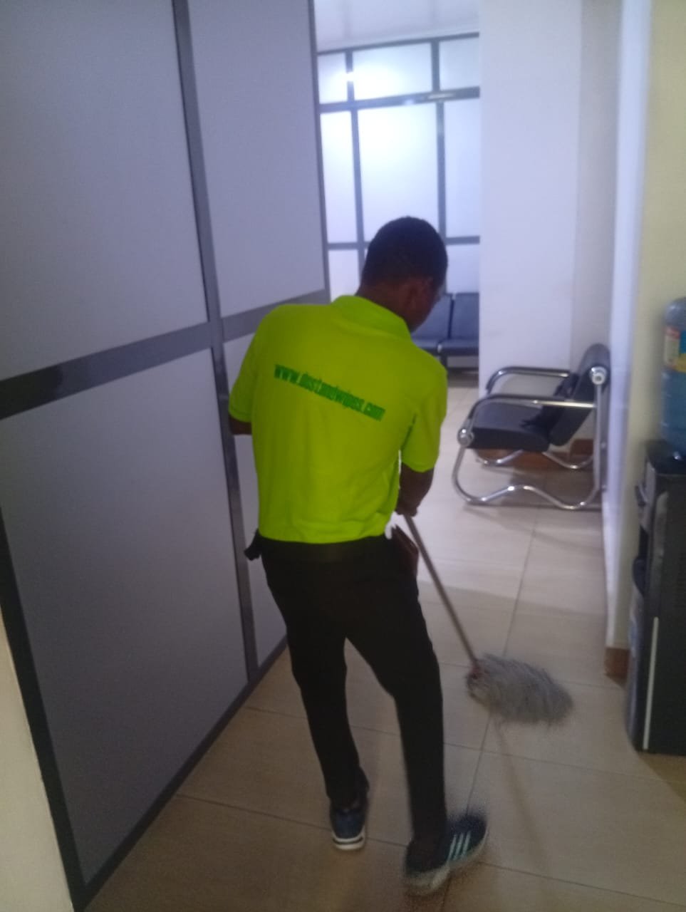 Dust and Wipes staff in lime uniform sweeping small office space