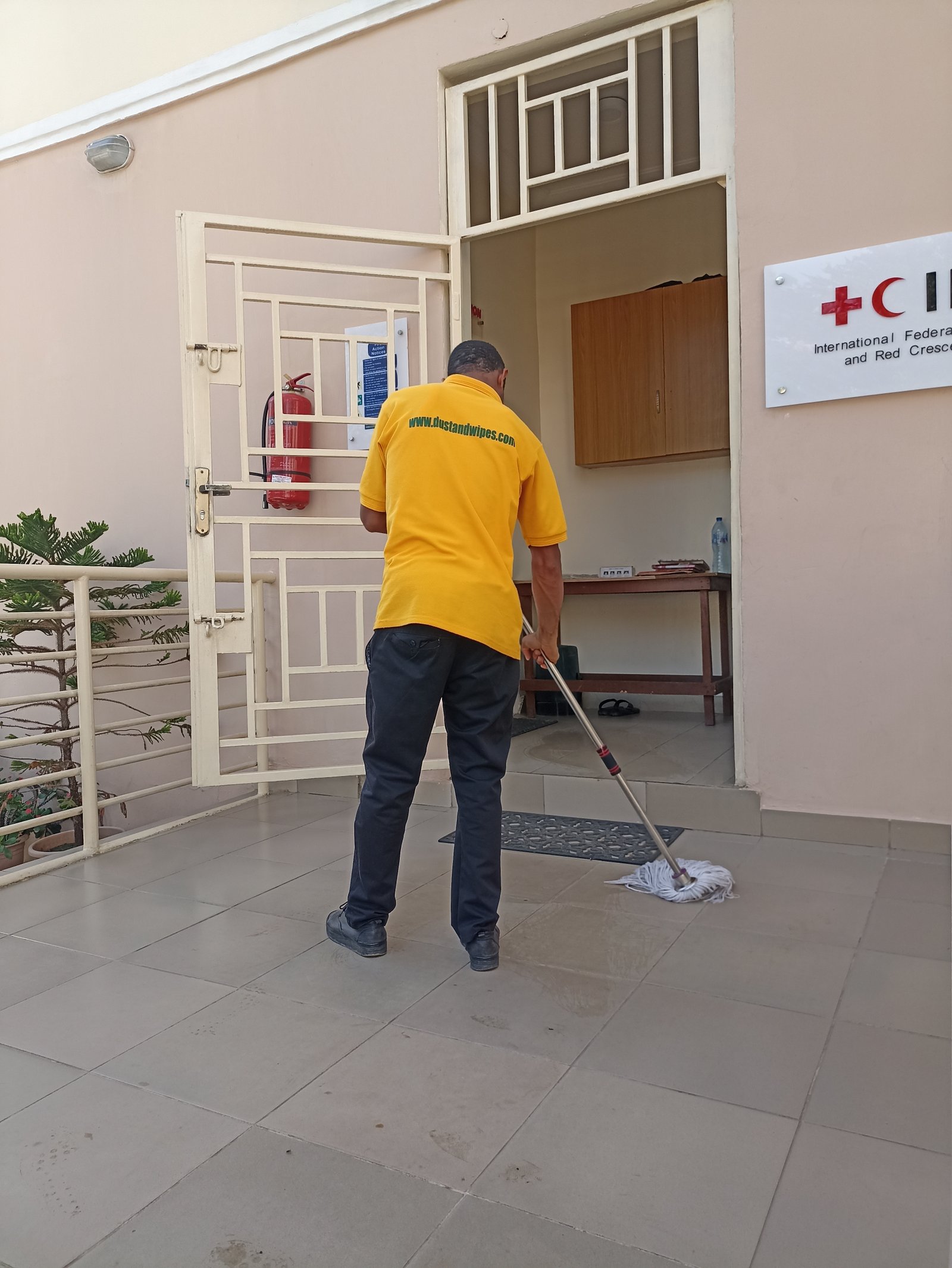 Dust and Wipes staff mopping clinic corridor at Red Cross facility